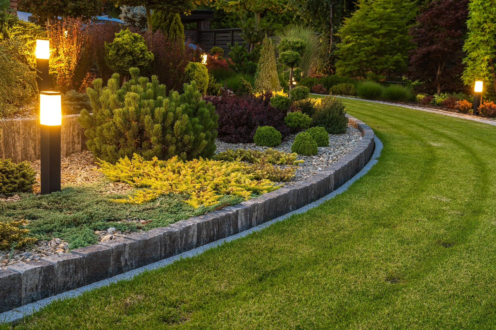 Aangelegde border met vaste planten en tuinverlichting langs een strak gazon